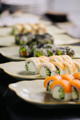 Assorted sushi rolls on plates in a restaurant setting, highlighting a variety of fresh ingredients