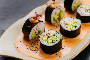 Sushi rolls on spicy sauce garnished with sesame and chili threads for an exquisite presentation