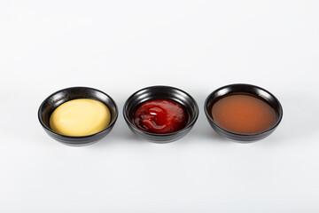 Three different sauces on a white background, ketchup, cheese sauce and chili sauce