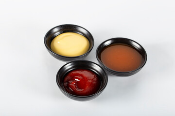 Three different sauces on a white background, ketchup, cheese sauce and chili sauce