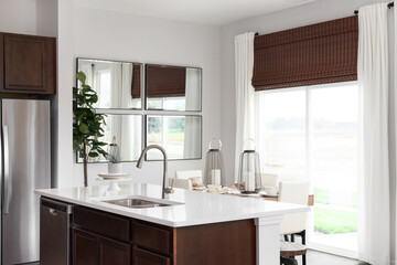 A kitchen detail with a wood island and white marble countertop looking towards a dining room in front of a bright sliding door.