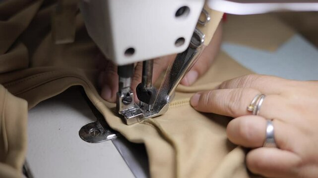 Sewing machines are working, producing clothes in a factory.