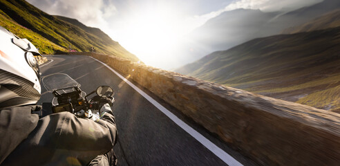 Detail of motorcycle handlebars. View from driver perspective, beautiful Alpine landscape in sunset...