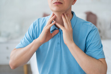 Thyroid gland inflammation, sore throat and cough, man with neck pain at home