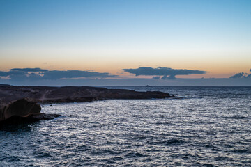 The sky is a beautiful shade of orange and the water is calm. The scene is peaceful and serene