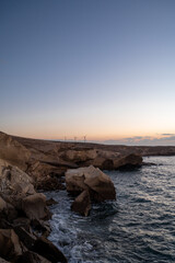The sky takes on a beautiful blue and orange hue as the sun sets. The water is calm and the rocks are jagged, vertical framing. © AlbertoRodriguez