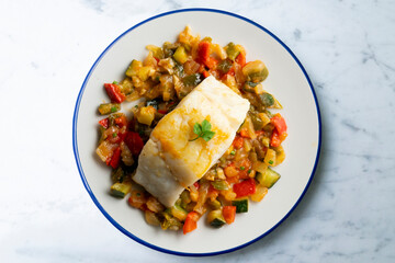 Cod with baked vegetables traditional Spanish recipe. Top view food.