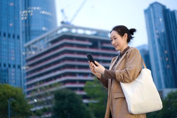 Fototapeta premium Young Woman Engaged with Smartphone in Modern Urban Landscape