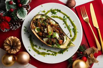 Eggplant stuffed with tomato and baked mozzarella. Food on a Christmas decorated table.