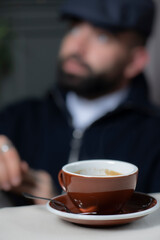 Coffee cup in coffee shop. Man with beard and mustache sitting in cafe and drinking coffee.