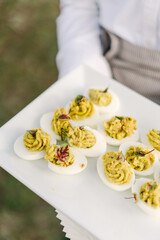 deviled eggs on white plate held by person