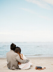 couple sitting on beach while hugging with copy space