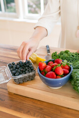 hand reaching for blueberries styled with food on butcher block