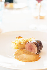 Elegant gourmet dish featuring succulent meat paired with creamy sides and rich sauce.