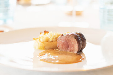 Gourmet dish featuring tender meat, creamy side, and savory sauce, beautifully plated for a fine dining experience.