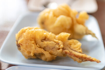 Close-up of crispy golden fried vegetable fritters on a white plate,.