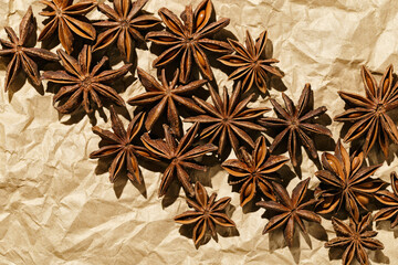 Anise stars background, top view close up macro photography fragrant spices dry anise seeds on crumpled baked paper, natural organic seasoning texture, food pattern, brown beige monochrome tone