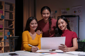 Three asian businesswomen working late and smiling at the office