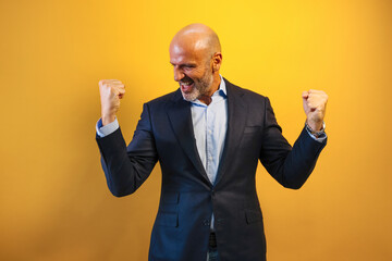 A man in a dark blue suit raises his arms in euphoria.