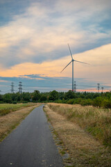 Road stretching into the horizon. Landscape with Wind Turbines and electricity transmission lines on a field in autumn, Berlin, Germany. Green power generation. Windmills for electric power production