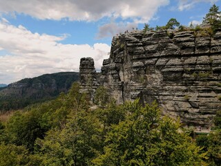 Bohemian Switzerland. Misty old rock on a hill in a forest. Beautiful countryside in Bohemia. Hiking adventure in nature. White and gray clouds. 