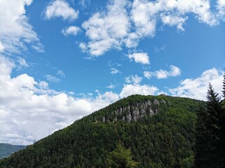 Cloudy sky in Mala Fatra. Rocky hill with a forest. Countryside in Slovakia. Hiking in nature. Blue and green colors. 