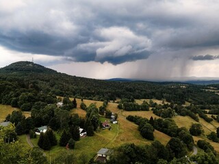 Rainy weather in Bohemian Switzerland. Beautiful cloudy sky. Foggy landscape. Storm over a forest, fields and cottages in the Czech countryside. 
