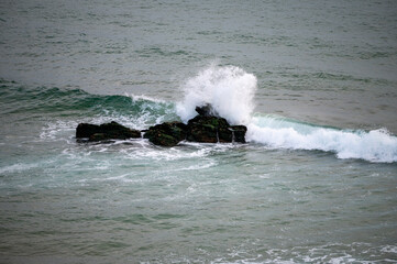 Der ozean trifft auf einen stein im meer und die welle sprüht gischt