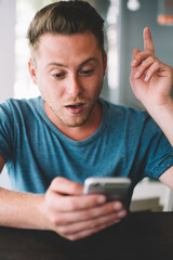 Smart millennial hipster guy holding finger up surprised with creating good idea for online publication on website for genius,young man amazed with solution for internet connection on cellphone gadget