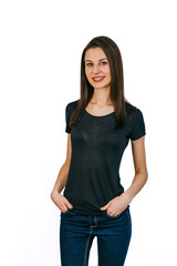 Confident young woman in casual wear on white backdrop. A young woman stands smiling with her hands...