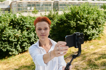 A young teacher with red hair takes a selfie on a sunny day.