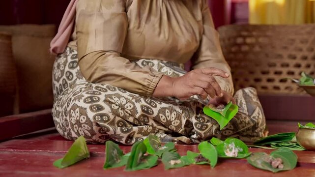 An asian woman prepares ingredients for betel nut chewing also called betel quid chewing or areca nut chewing