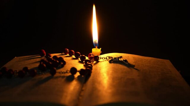 Holy bible, rosary and candle on black backround. Religion concept. 
