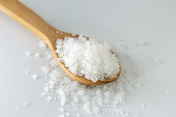 Organic rock salt in wooden spoon on white background. Transparent, healthy rock salt extracted in Turkey.