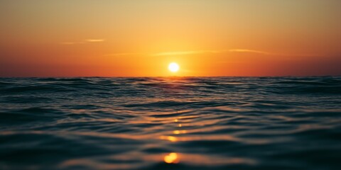 Obraz premium The sun is setting over the ocean, casting a warm glow on the water. The sky is a mix of orange and pink hues, creating a serene and peaceful atmosphere. The water is calm and still
