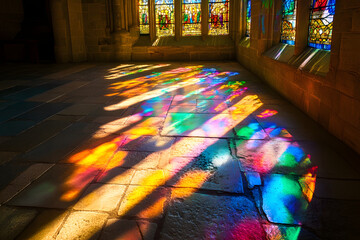 a stained glass window in an old cathedral, with the sunlight casting colorful reflections on the stone floor