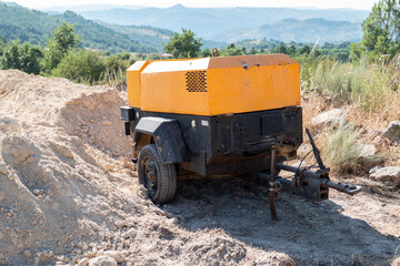 Em meio à natureza e a um canteiro de obras um compressor Industrial em ação