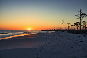 beautiful sunset along beach as waves roll in and out over warm reflecting sand. Tranquil and scenic view of vacation destination.