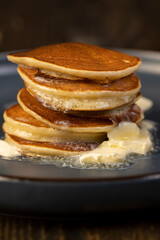 thin hot pancakes with butter on a blue plate