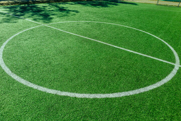 Obraz premium The marking of the center of the soccer stadium. Empty soccer field with an artificial green turf