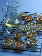 Candied citrus fruits and a glass jar on a wire rack.