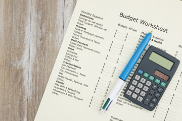 Monthly personal budget with a pen and calculator on wood desk