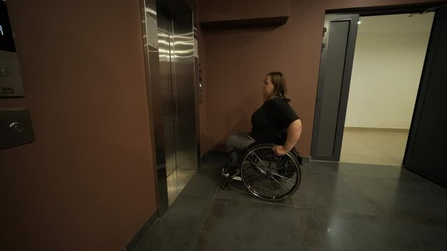 A woman in a wheelchair waits in front of an elevator in a building, emphasizing accessibility and mobility in public infrastructure. The image conveys independence and inclusive design for all users.