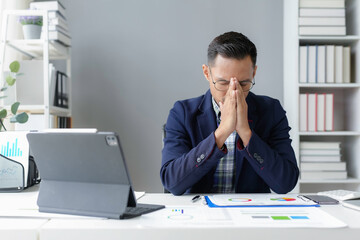 Stressed asian businessman suffering headache at workplace