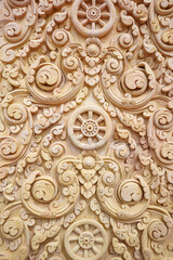 Detail of Dharmachakra Wheel sculpture with delicate etched floral design pattern on brown sandstone wall in temple,Traditional Thai style stone craving at Wat Phumanfah in Thailand. Vertical.