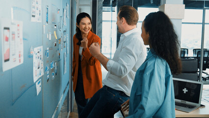 Portrait of group of businesspeople putting sticky notes on glass board. Professional business team brainstorming marketing strategy while stick notes on glass wall. Business meeting. Manipulator.