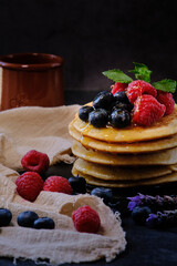 pancakes with berries and honey on dark background