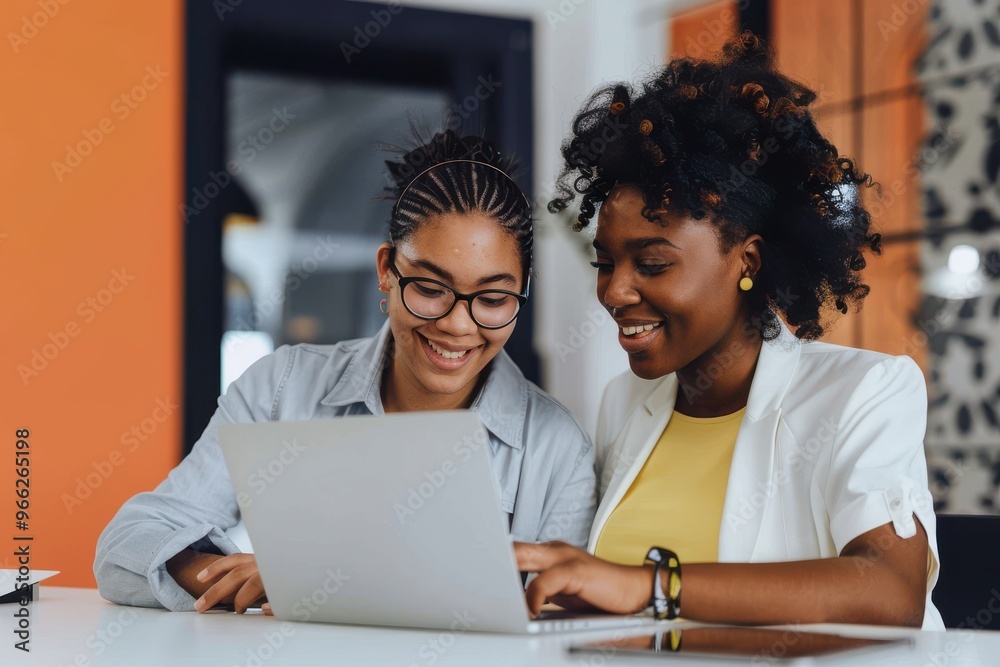 Wall mural Nothing gets results like a go getter team Shot of two young businesswomen using a laptop together in a modern office