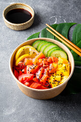 Poke bowl with salmon, mango and vegetables vertical photo grey background