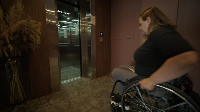 A woman in a wheelchair approaches an elevator in a hotel lobby, showcasing accessible accommodations and modern design. The scene emphasizes mobility, independence, and inclusivity in hospitality.